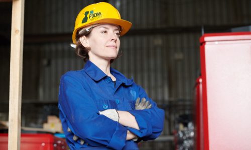 Waist up portrait of empowered woman wearing hardhat posing confodently standing in industrial workshop, copy space